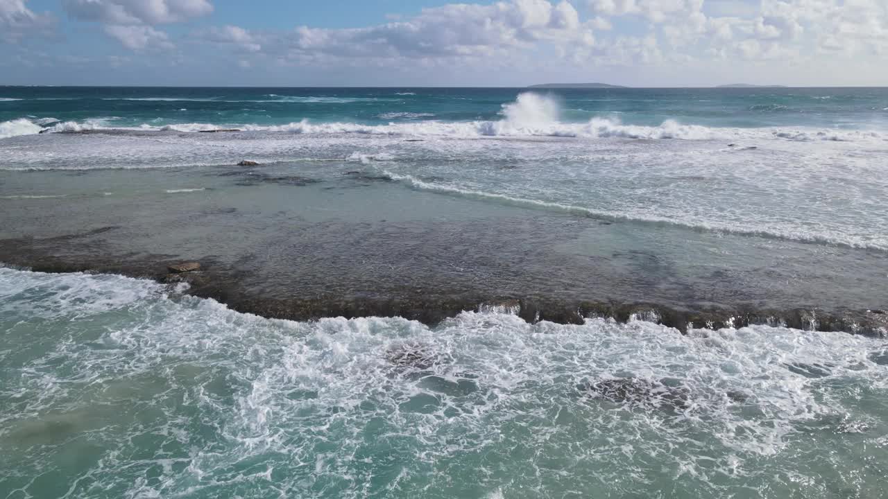 海浪有规律地冲击着岩石海滩视频下载