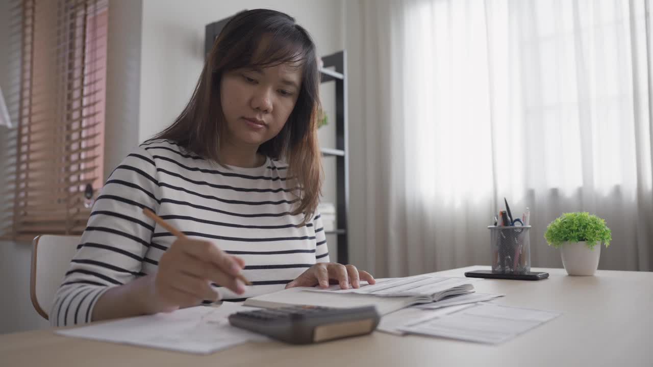 用计算器和便签本分析和计算家庭财务账单视频素材