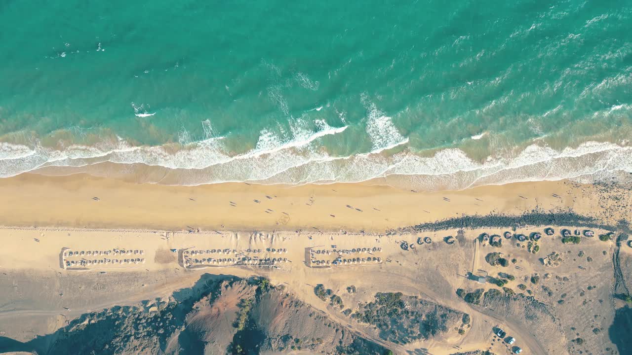 夏天的海景美丽的波浪，蓝色的海水在阳光明媚的日子。西班牙，加那利岛，埃斯昆佐海滩。海上鸟瞰图，热带自然美丽明亮的海浪飞溅和沙滩沙滩夕阳视频素材