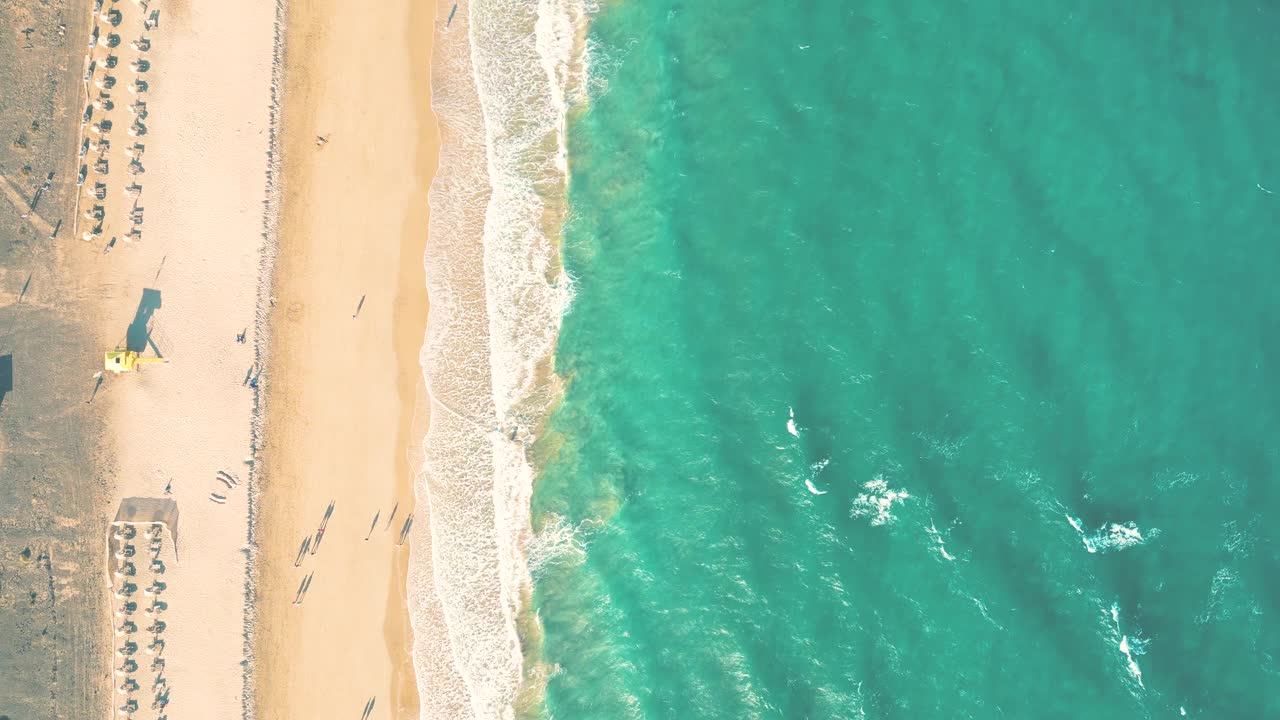 夏天的海景美丽的波浪，蓝色的海水在阳光明媚的日子。西班牙，加那利岛，埃斯昆佐海滩。海上鸟瞰图，热带自然美丽明亮的海浪飞溅和沙滩沙滩夕阳视频素材