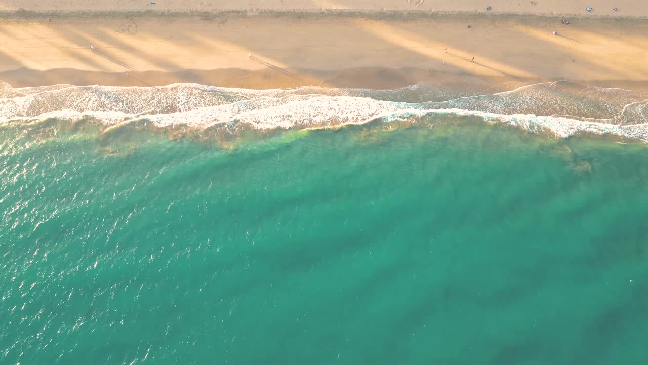 夏天的海景美丽的波浪，蓝色的海水在阳光明媚的日子。西班牙，加那利岛，埃斯昆佐海滩。海上鸟瞰图，热带自然美丽明亮的海浪飞溅和沙滩沙滩夕阳视频素材