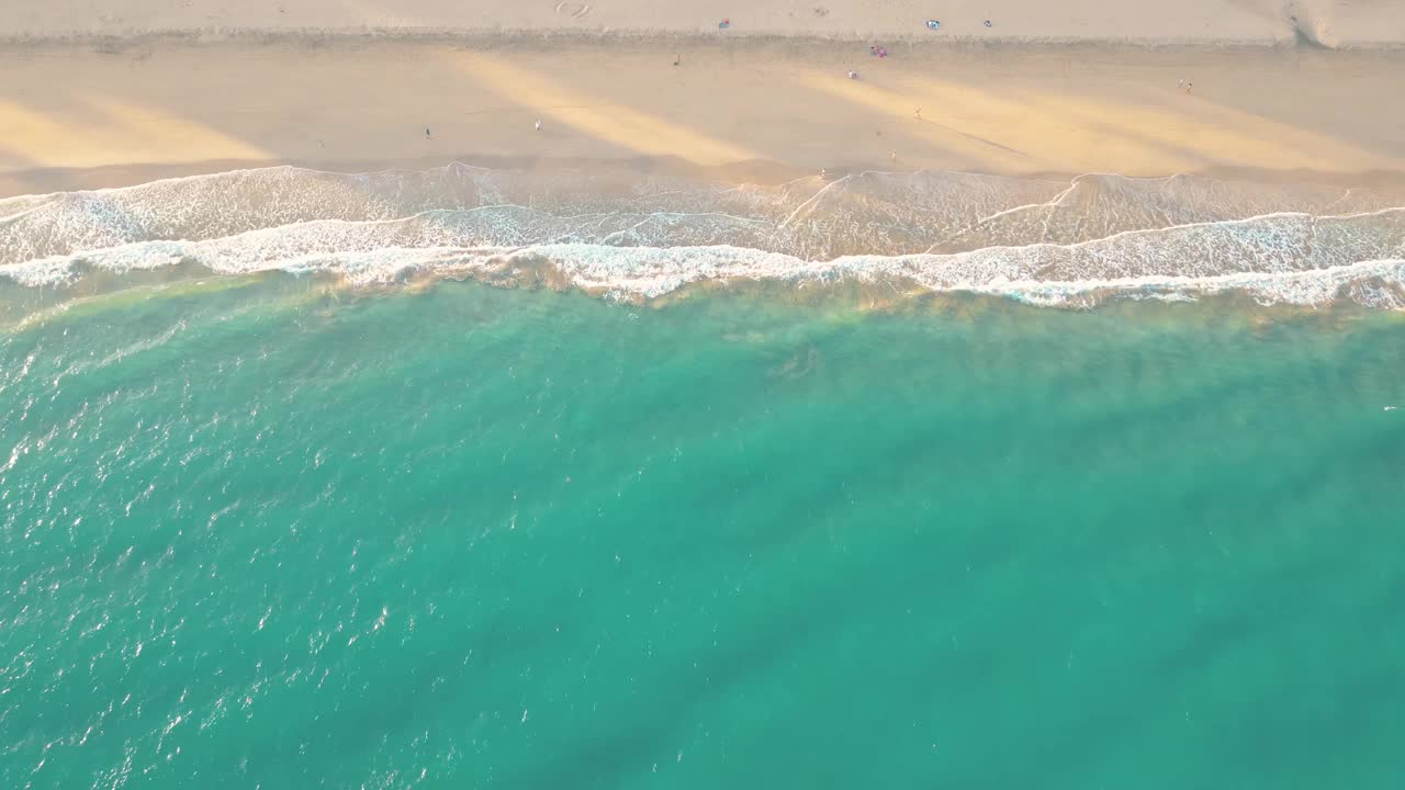 夏天的海景美丽的波浪，蓝色的海水在阳光明媚的日子。西班牙，加那利岛，埃斯昆佐海滩。海上鸟瞰图，热带自然美丽明亮的海浪飞溅和沙滩沙滩夕阳视频素材