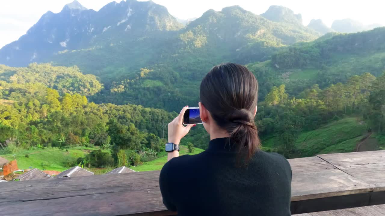 慢动作4k坐着的女人用手机拍摄前面有雾和阳光的山视频素材