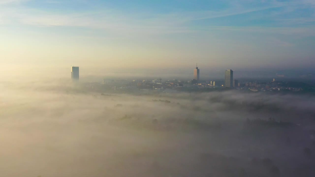 在一个雾蒙蒙的早晨，无人机在斯德哥尔摩的Kista拍摄远处摩天大楼的全景视频下载