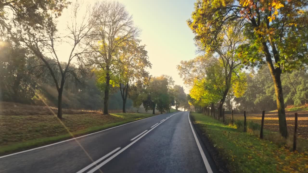 秋天日落时汽车行驶在柏油路上视频素材