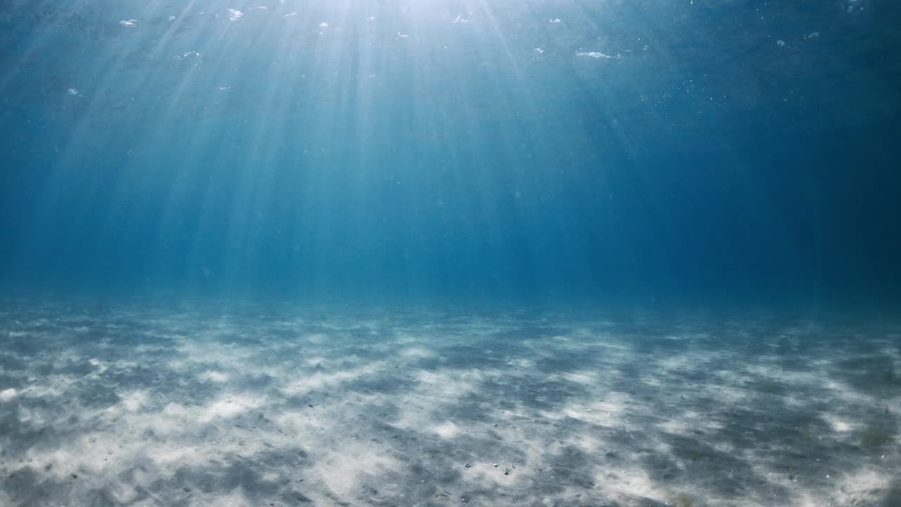 透明清澈的蓝色海洋，阳光和沙质海底水下视频素材