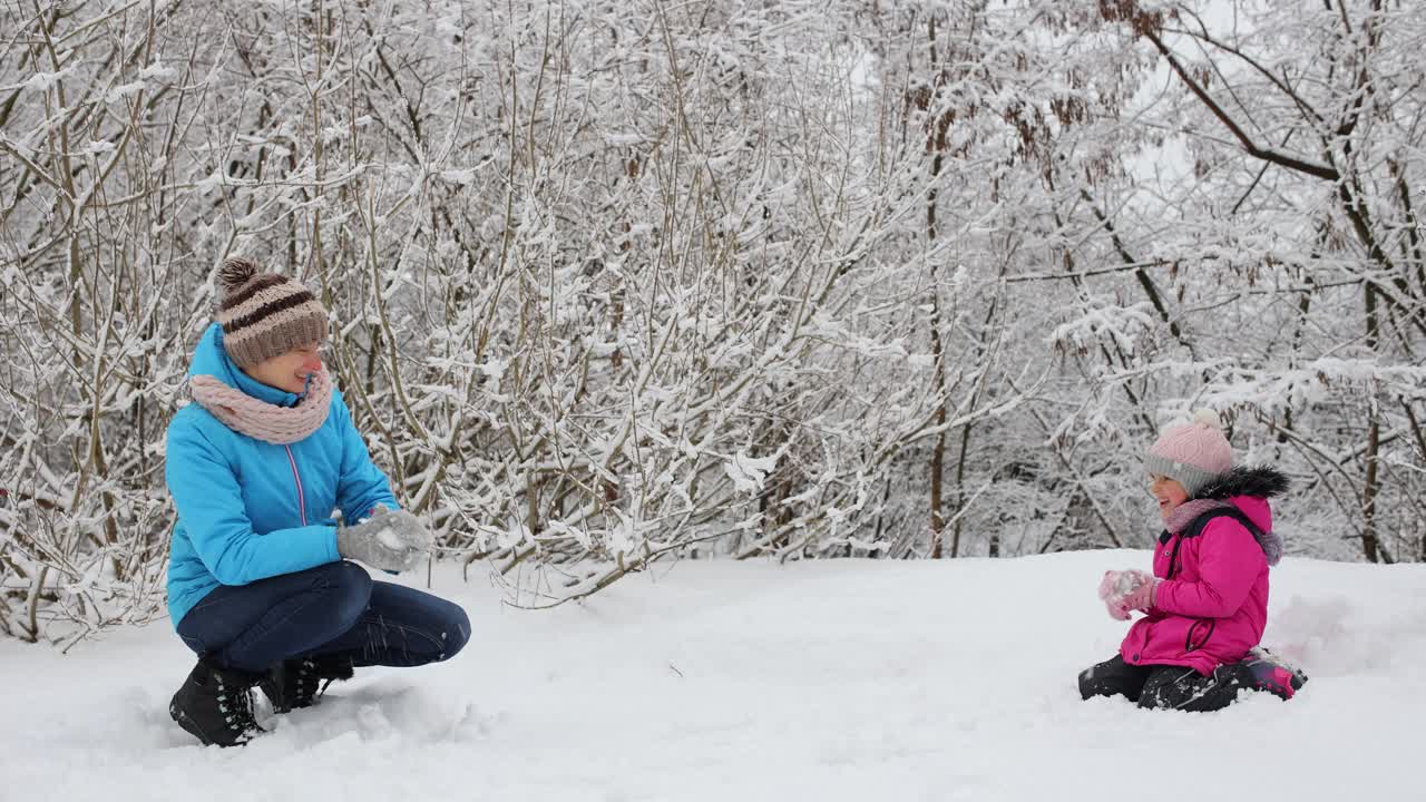 妈妈和女儿在冬天的雪地里玩得很开心视频下载