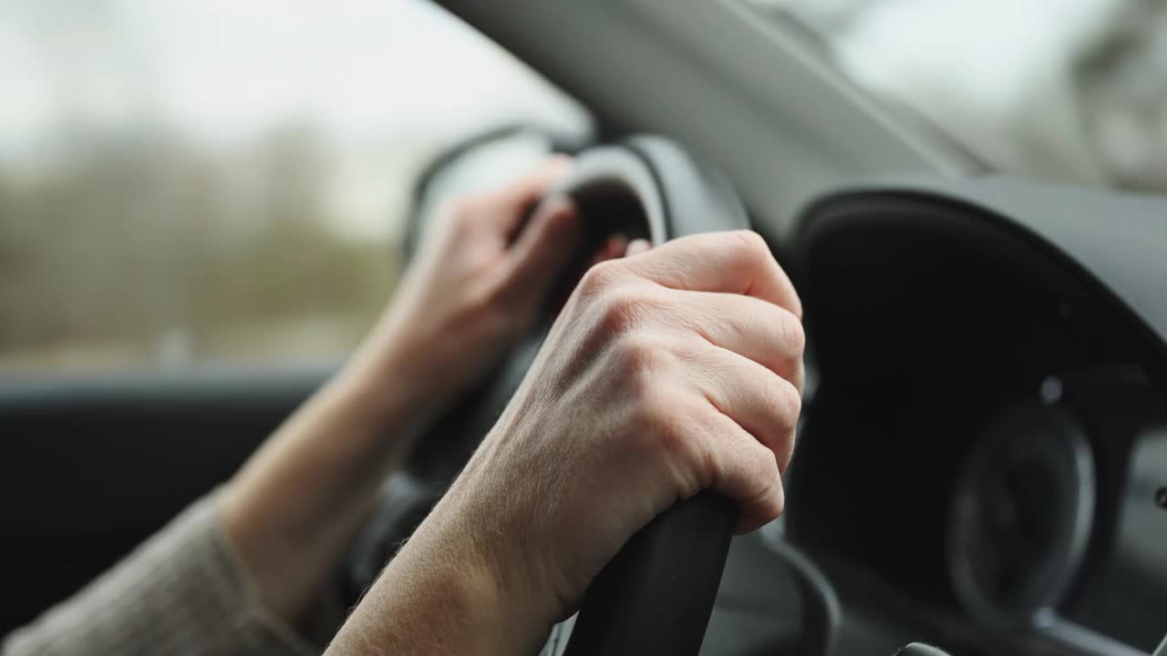 女司机正在乡间小路上开车，手放在方向盘上的特写视频素材