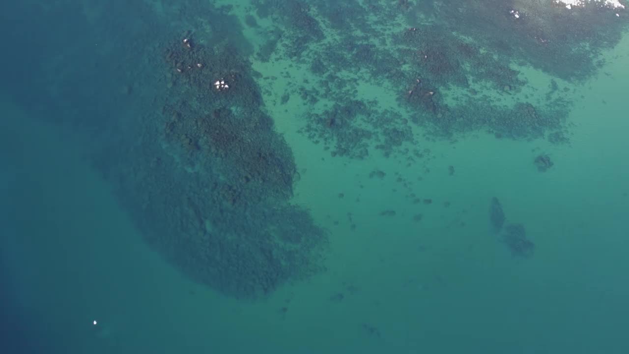 冬季，一架高空飞行的4K无人机在加州太浩湖上空拍摄。镜头向下朝向水晶般清澈的蓝色海水，然后慢慢地向上倾斜并向右旋转。视频素材