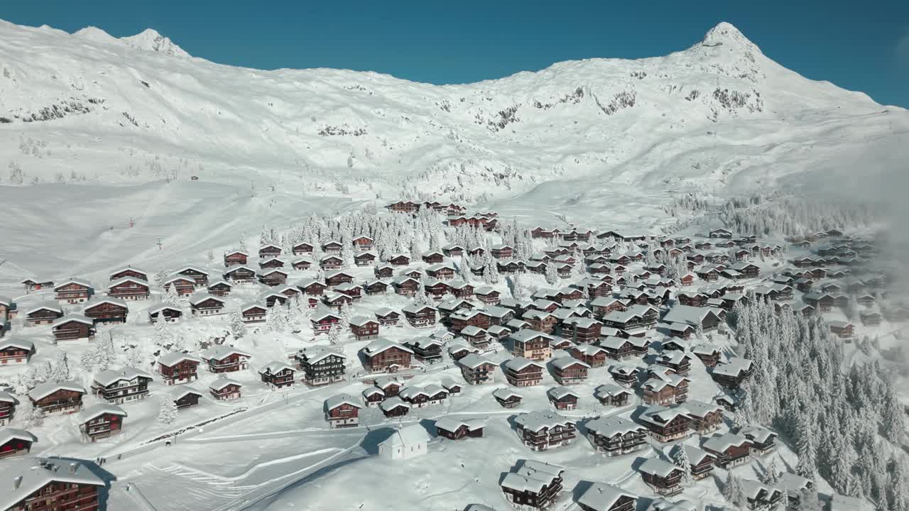 冬季滑雪胜地的航拍照片。有许多小屋的小村庄，背景是滑雪场。冬天的风景视频素材