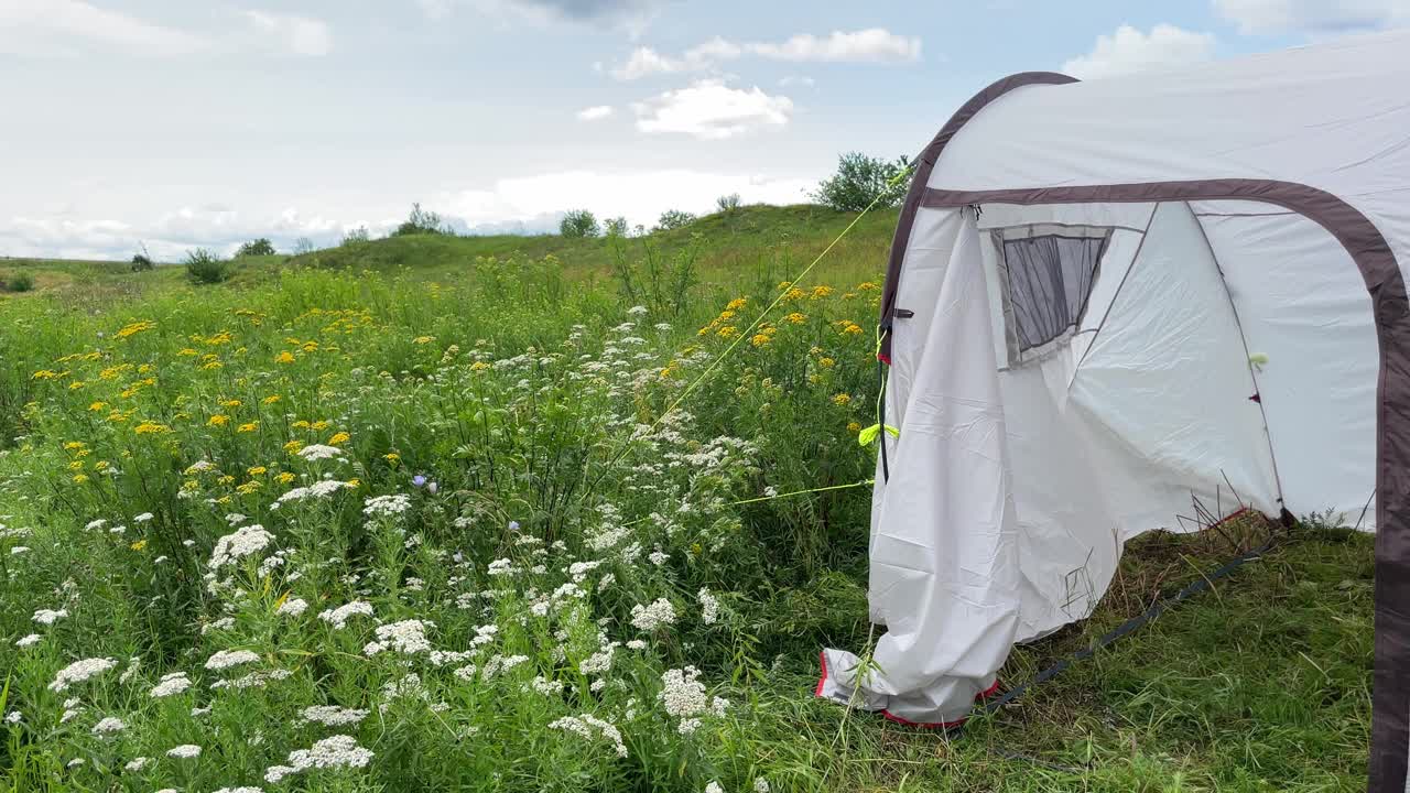 在一个阳光明媚的夏日，帐篷搭在一片盛开的田野中央，是户外休闲的好去处。视频素材