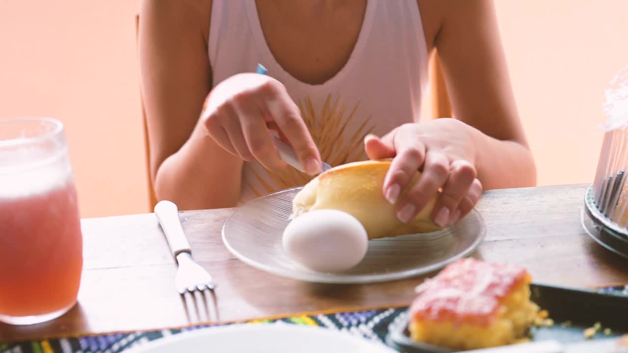 年轻女子在早餐桌上切面包视频素材