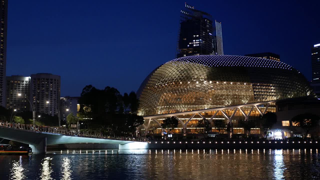 夜间建筑在新加坡滨海湾地区周围以灯光装饰和摩天楼为背景的办公金融大楼视频素材