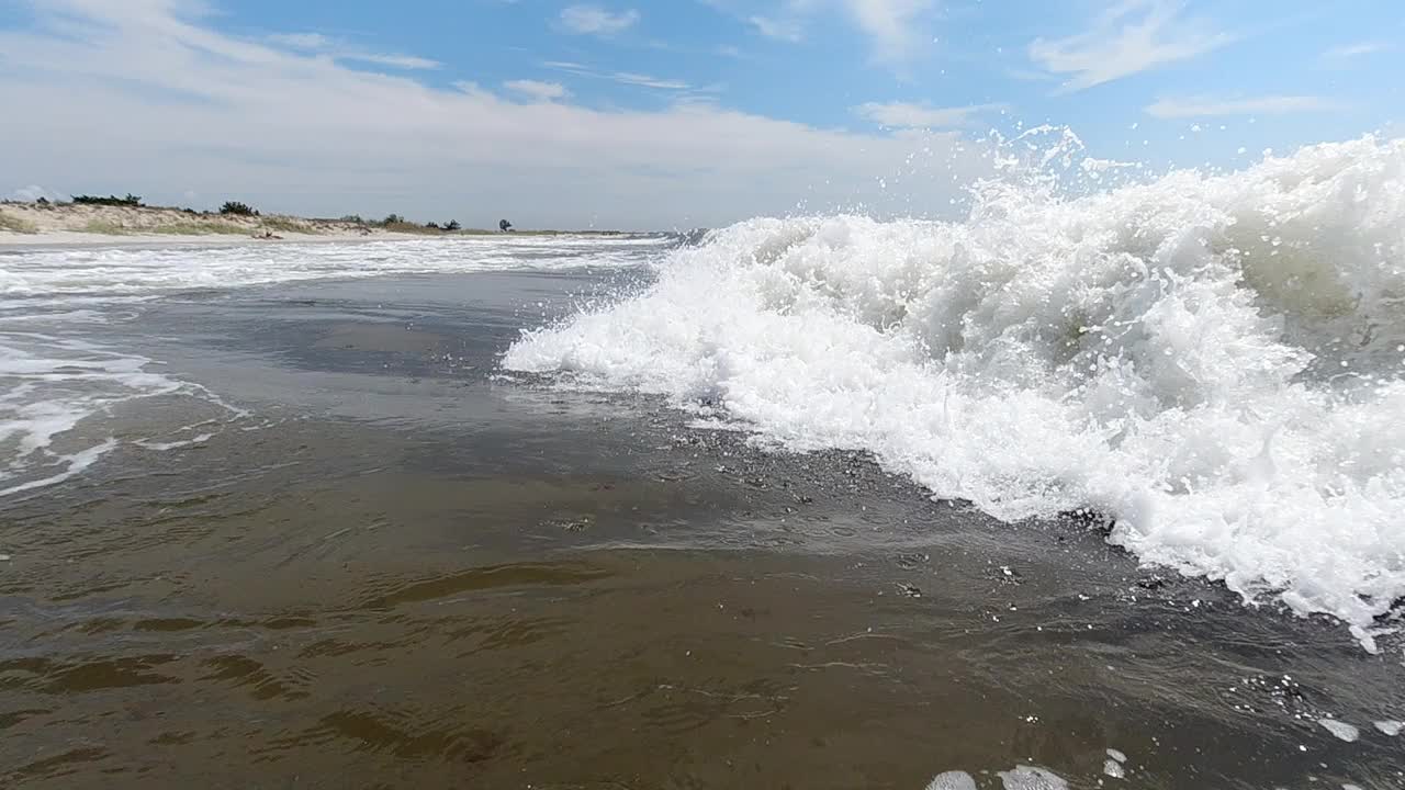 巨大的海浪拍打着海岸，溅起白色的水花。慢动作视频下载