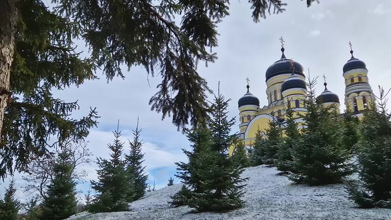 汉沽寺户外冬景。传统的东正教教堂坐落在摩尔多瓦共和国的白雪皑皑的树林中。东欧大教堂的传统建筑风格视频素材