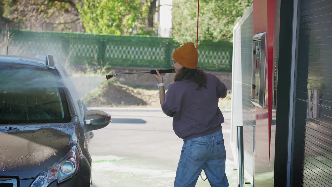 一位年轻的白人妇女在自助洗车店洗车视频素材