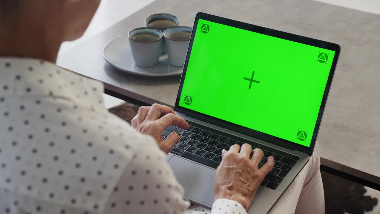 成熟女人在室内用绿屏笔记本电脑打字视频素材