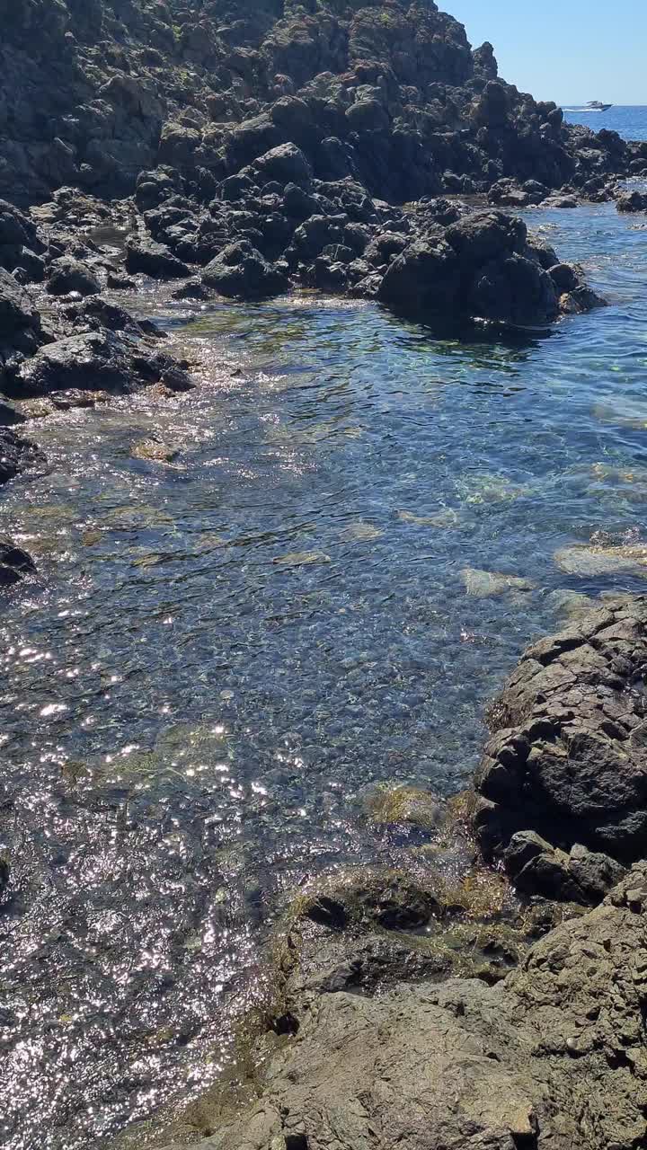 美丽的海景，清澈的海水，岩石和风景如画的海岸。远处可以看到厄尔巴岛。意大利，皮昂比诺，法尔科内湾。视频素材