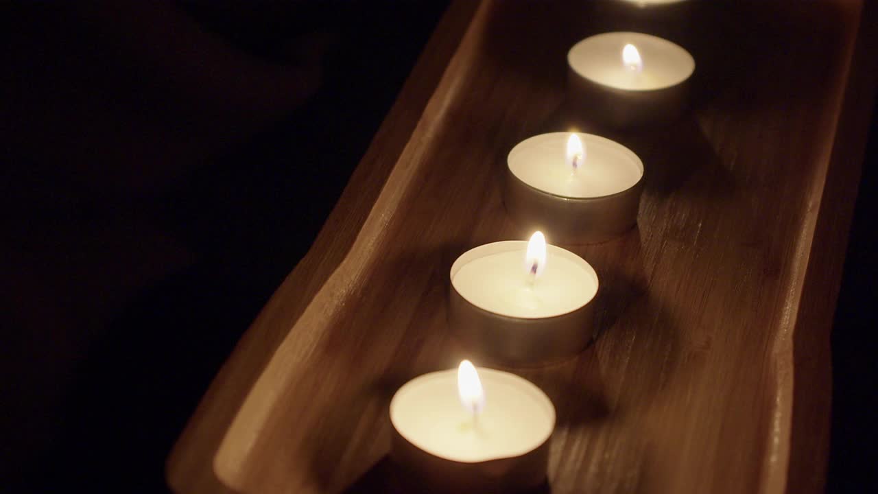 黑暗忧郁的背景:茶蜡烛燃烧在装饰木托盘视频素材