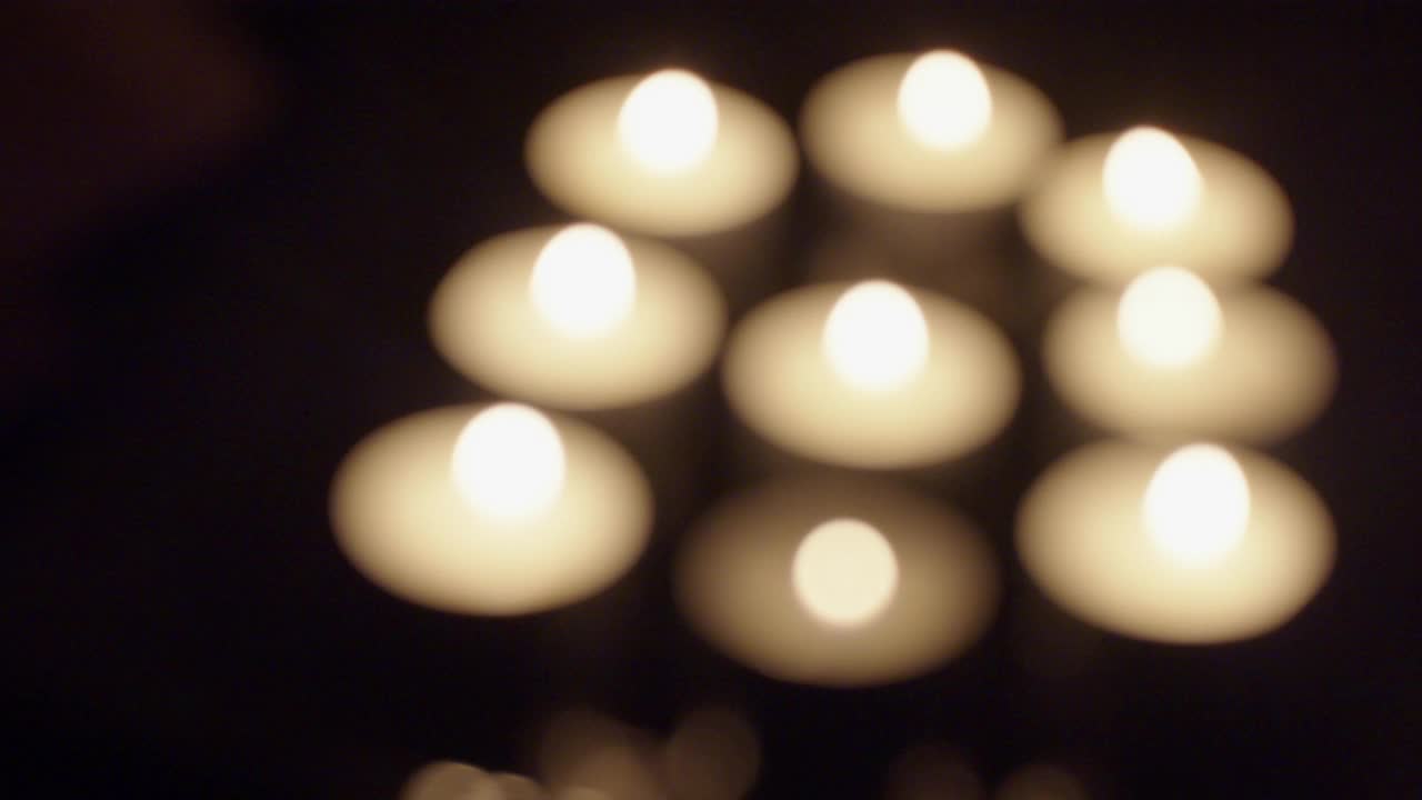 一组散焦的茶蜡烛在黑暗的背景下燃烧，复制空间视频素材