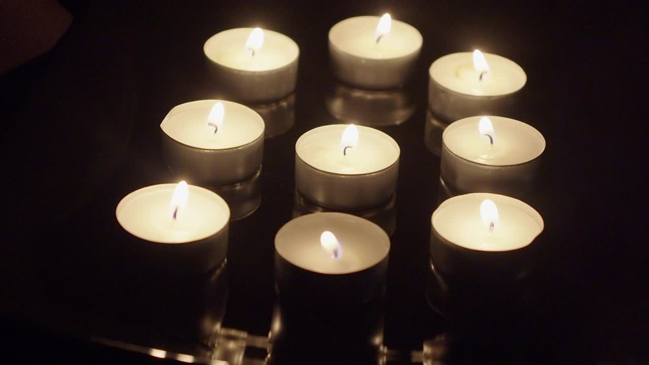 在漆黑的房间里，九支茶烛在反射面上燃烧着火焰视频素材
