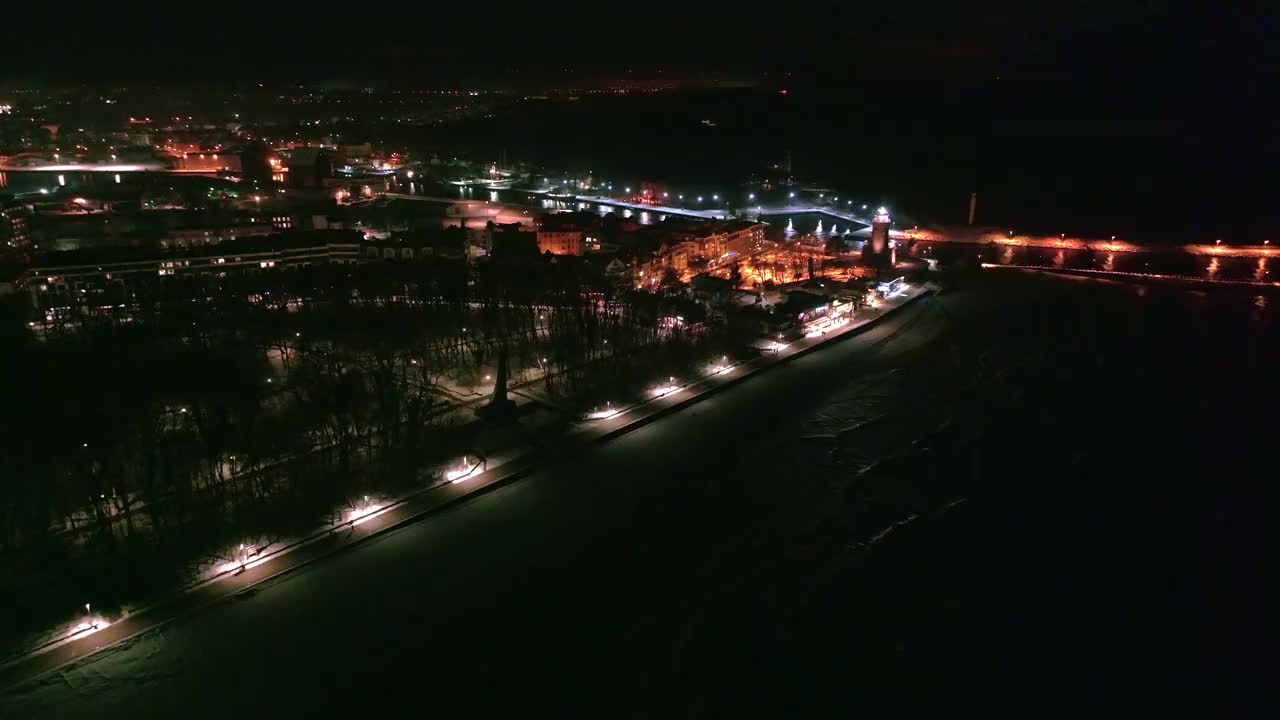 一段令人着迷的无人机拍摄了Kołobrzeg灯塔在冬天的夜晚，用宁静迷人的光芒照亮了沿海景观。视频素材