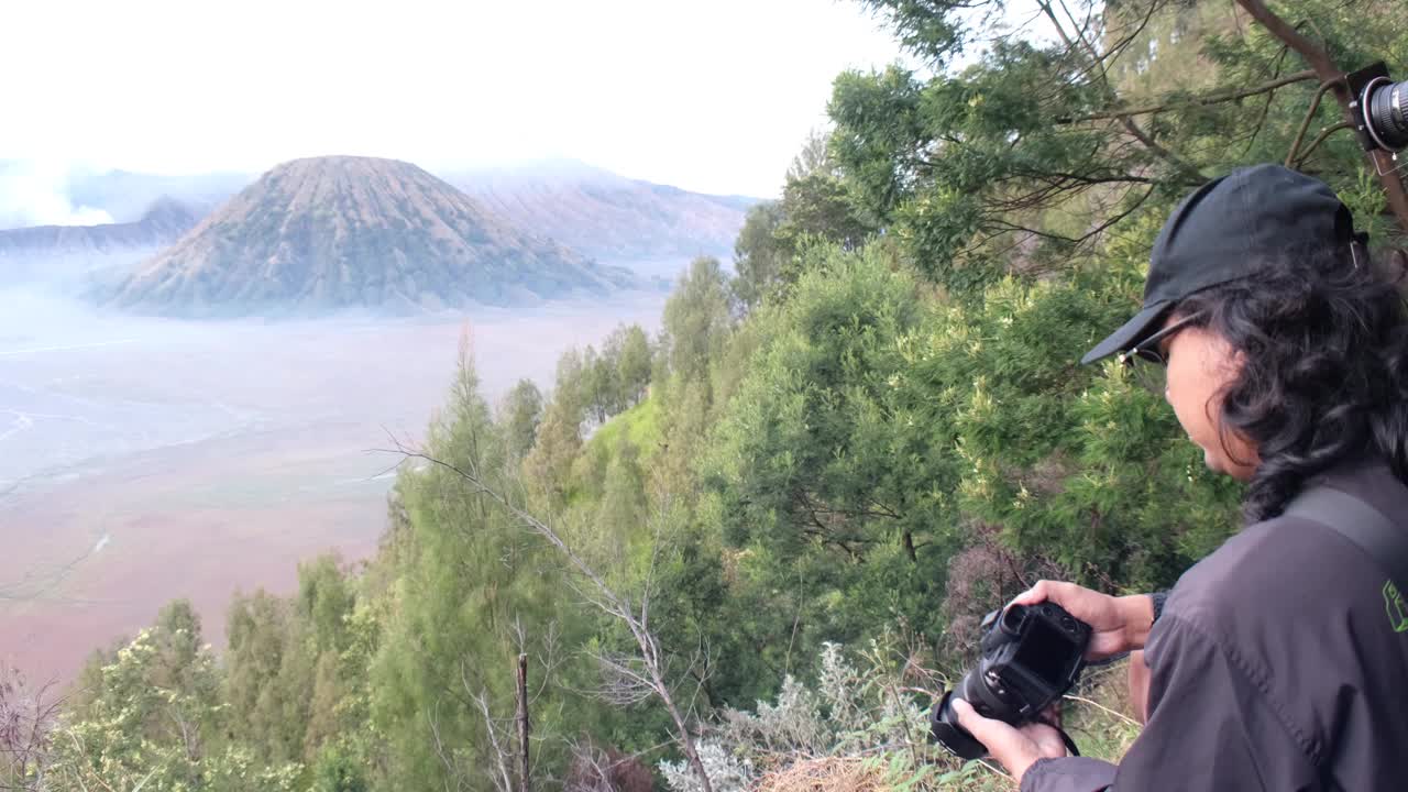 风景摄影师正在雾蒙蒙的清晨日出中拍摄布罗莫山的美景视频素材