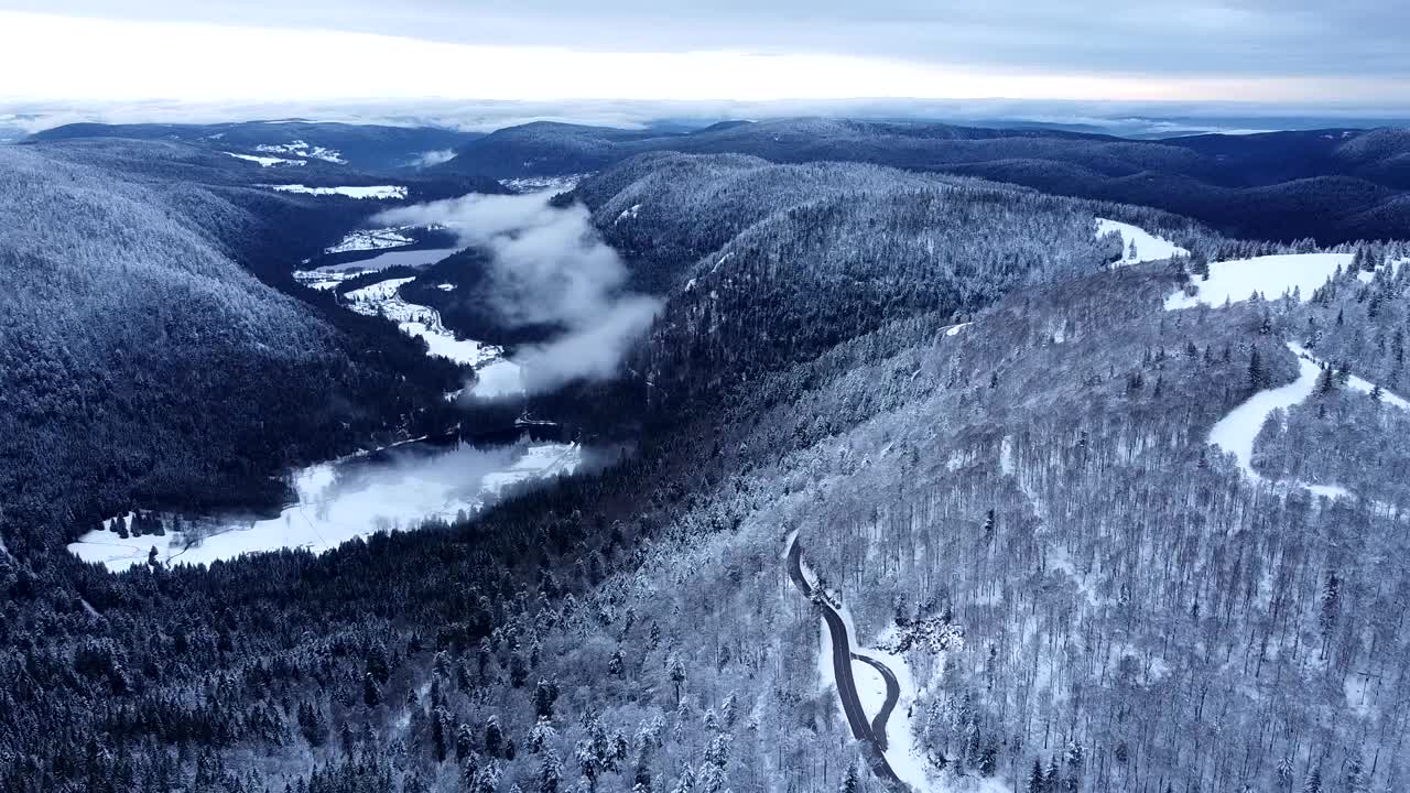 在法国上孚日的冬季，从空中缓慢地俯瞰白雪皑皑的湖泊山谷视频素材