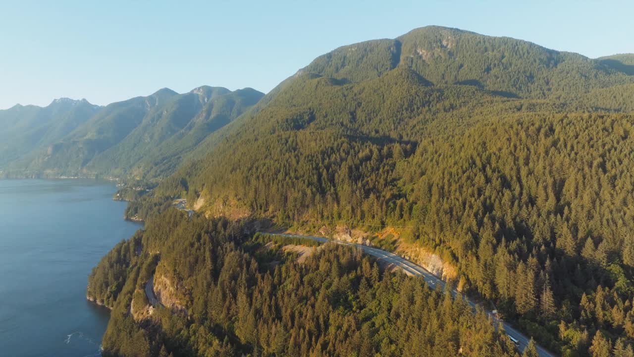 不列颠哥伦比亚省马蹄湾沿岸茂密的森林景观上的金色光线。不断上升的无人机显示出山脉和加拿大横贯公路的广阔视野。视频素材