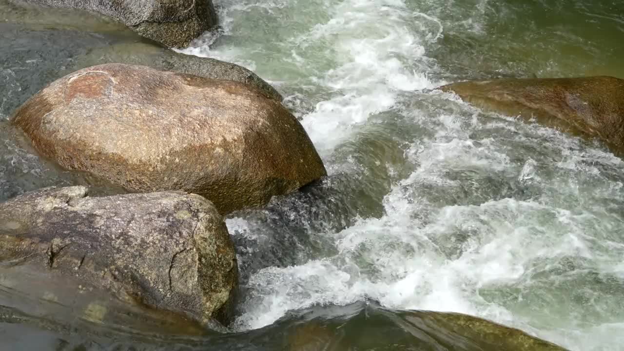 特写镜头展示了水和纹理岩石之间宁静的相互作用。视频素材