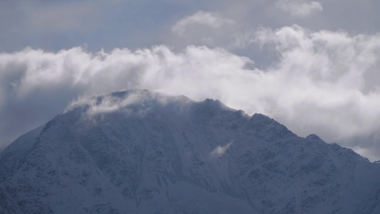 灰色的天空下，一座覆盖着雪和云的山视频素材