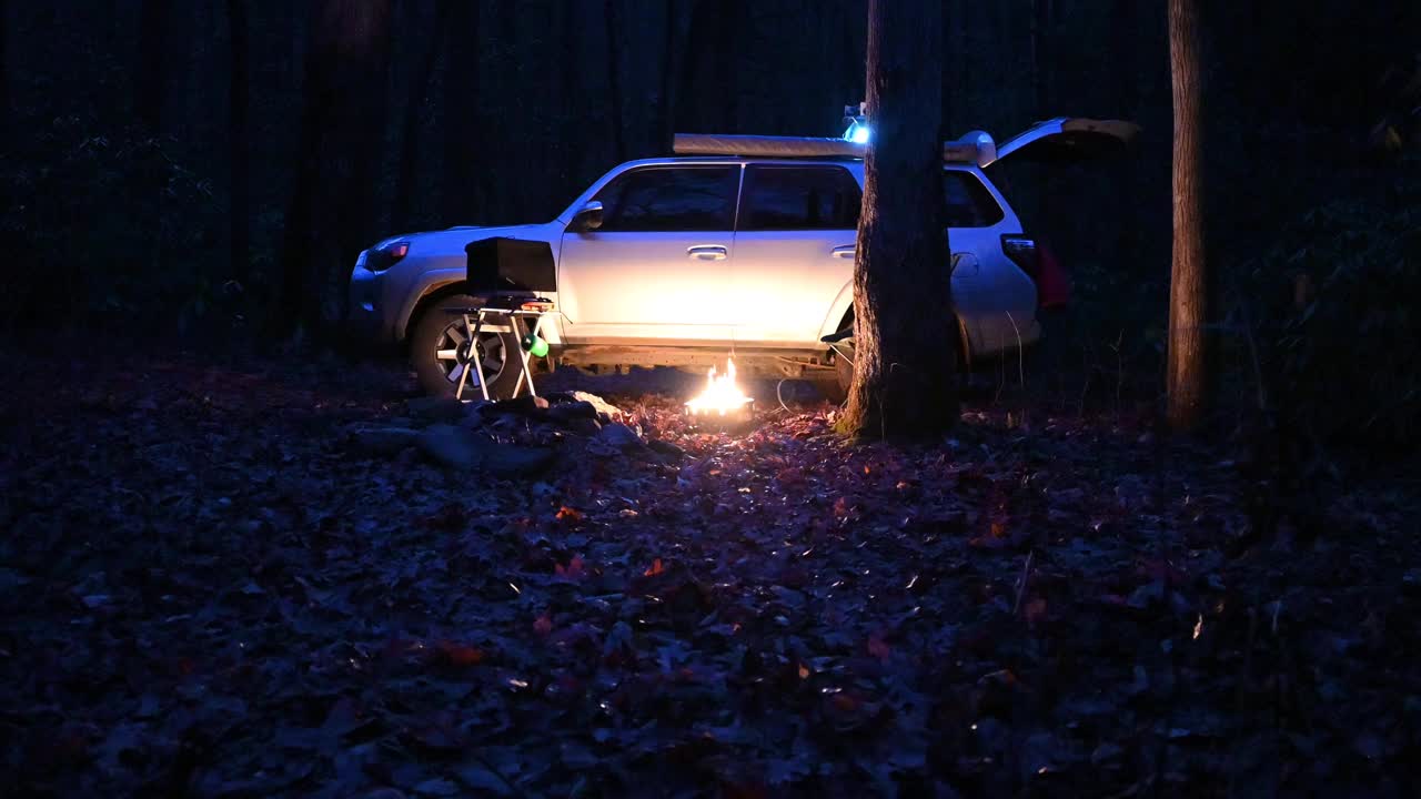 在夜间登陆营地在冷色丙烷火坑和野营烤箱炉在折叠桌上视频素材