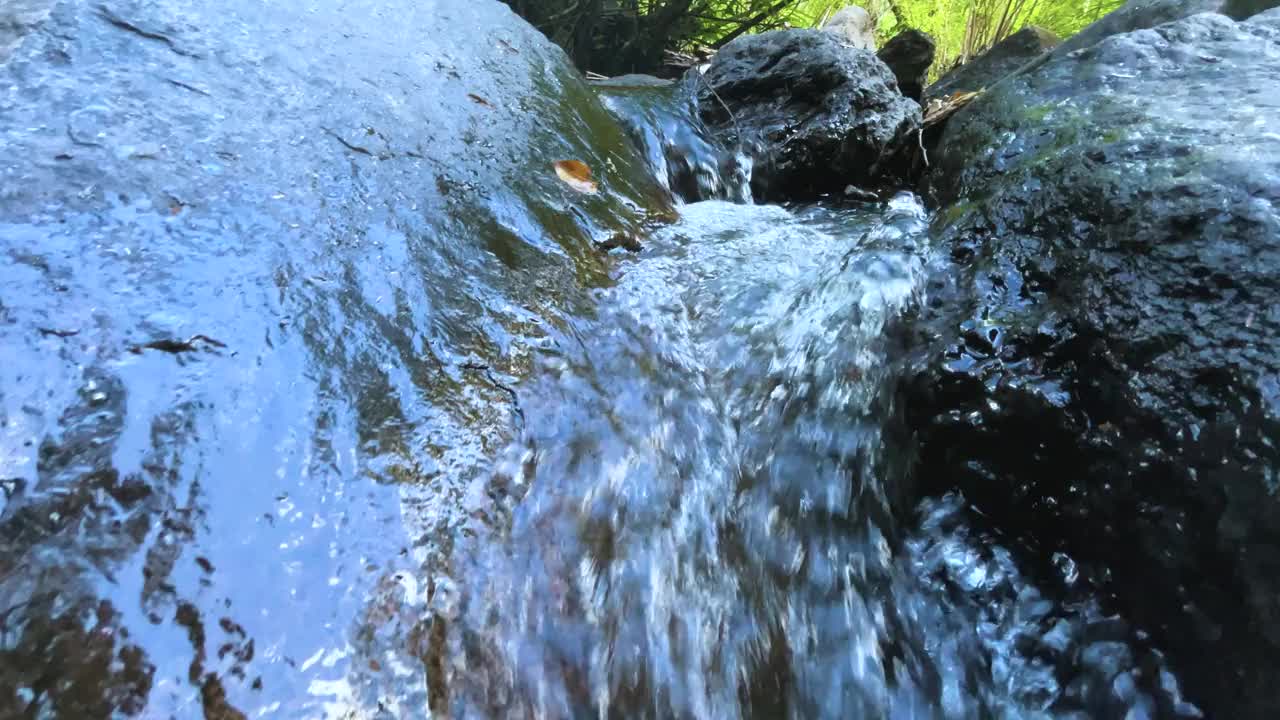 夏天绿色森林里湍急的小溪，清澈的小瀑布。岩石和圆木上长满了苔藓。用慢动作拍摄动态照片视频下载