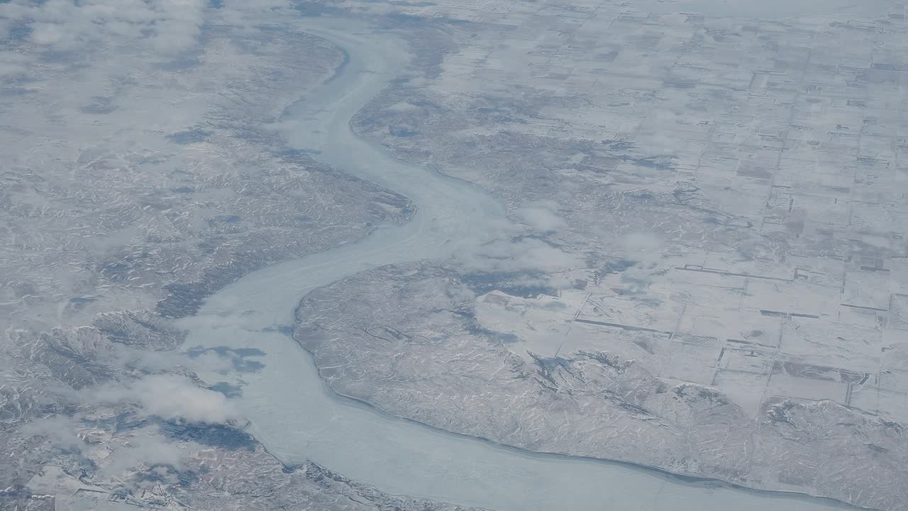 冬季在北美上空飞行。飞机窗外的风景。冰冻的河流和平原上的积雪视频素材