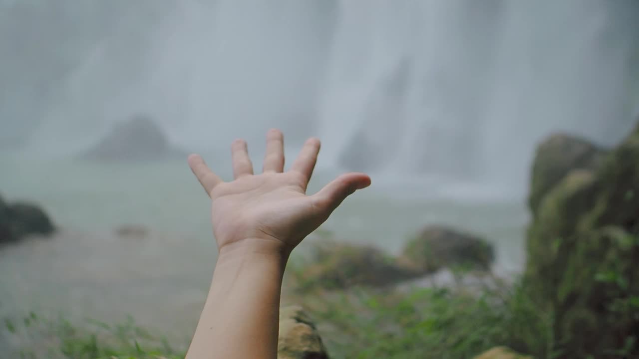 自然界中一只手在瀑布中移动的慢动作细节。旅行和冒险的概念视频下载