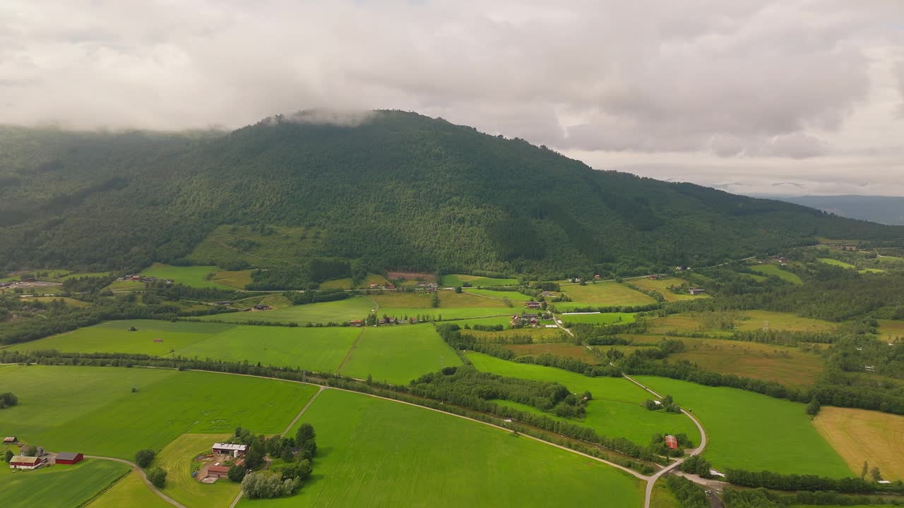 挪威西部的乡村景观，绿色的牧场和森林覆盖的山脉。无人机鸟眼。视频素材