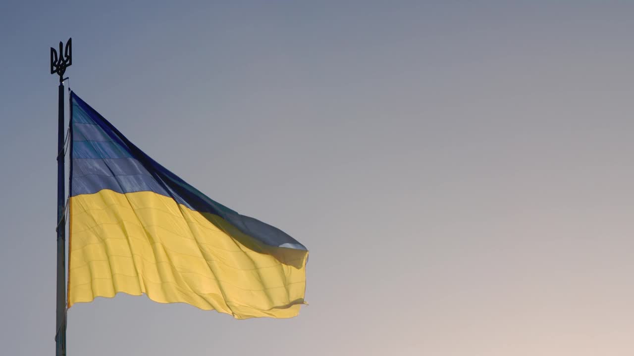 乌克兰国旗。一面巨大的乌克兰国旗在天空中飘扬的慢镜头。蓝色和黄色是乌克兰的国家象征。旗杆上的大旗。视频下载