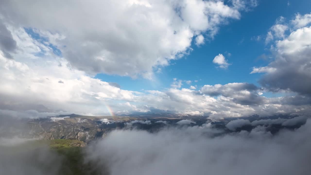 在山区云层上方飞行的彩虹鸟瞰图。日落时，山上的彩虹伴着云彩视频素材