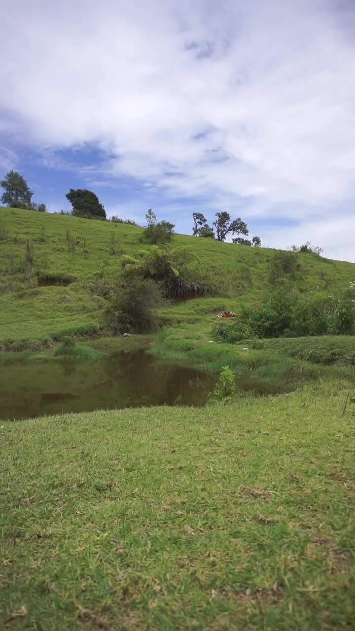 自然风光山脉自然全景丘陵，和森林的高大的绿树和斜坡的绿色种植园在多云的蓝天视频素材