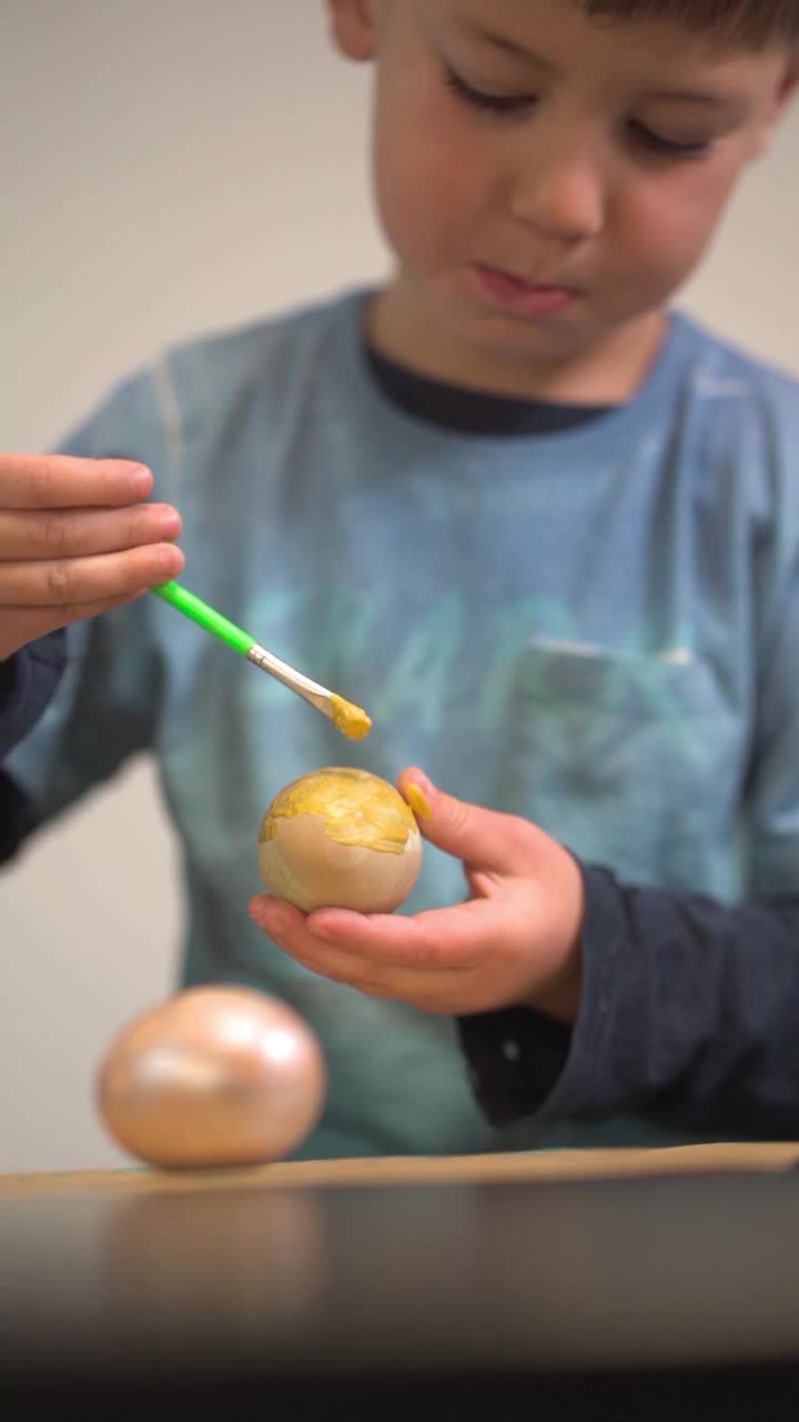 一个小孩子创造性地画着一个复活节彩蛋。复活节假期准备视频素材