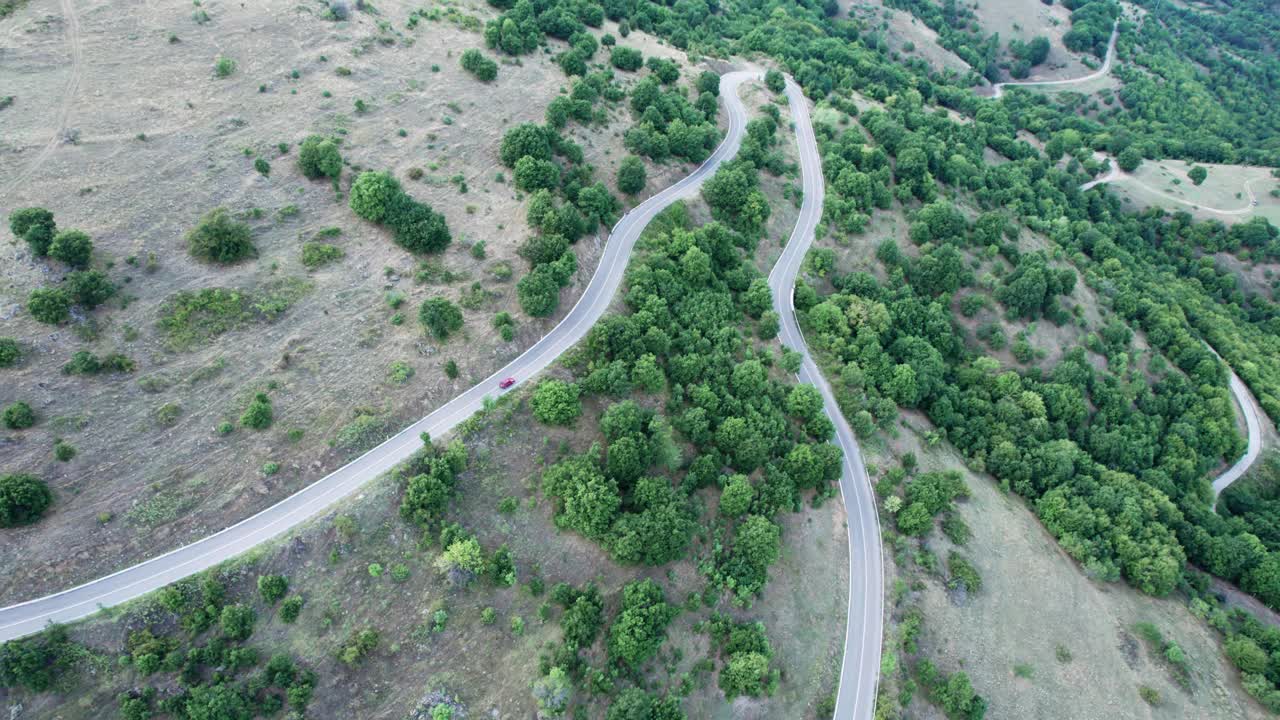 红色赛车在弯弯曲曲的山地乡村公路上疾驰，高速鸟瞰视频素材