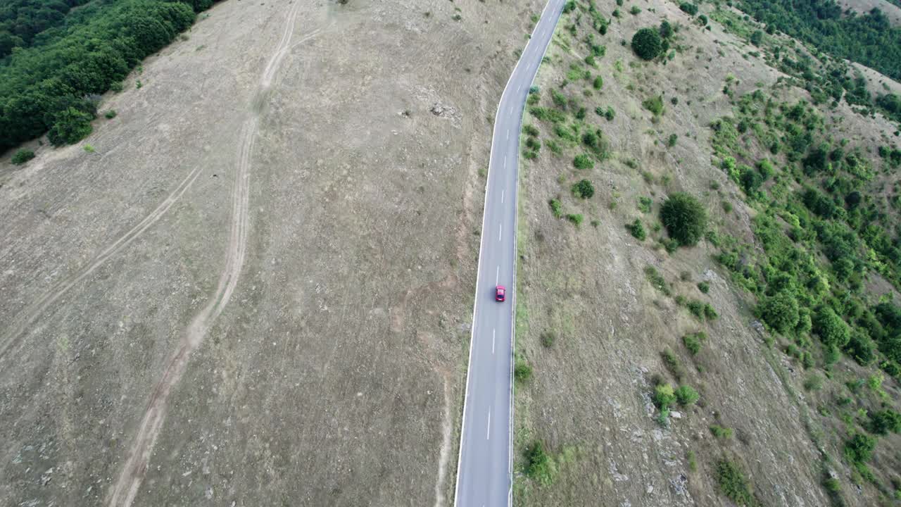 红色赛车在弯弯曲曲的山地乡村公路上疾驰，高速鸟瞰视频素材