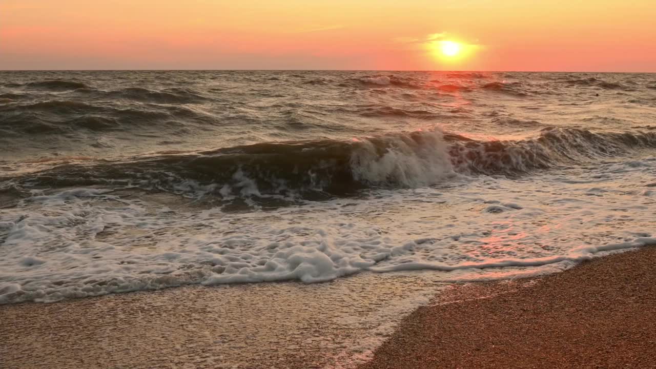 日落时的海岸和海浪。傍晚的夕阳在海面上慢动作视频下载