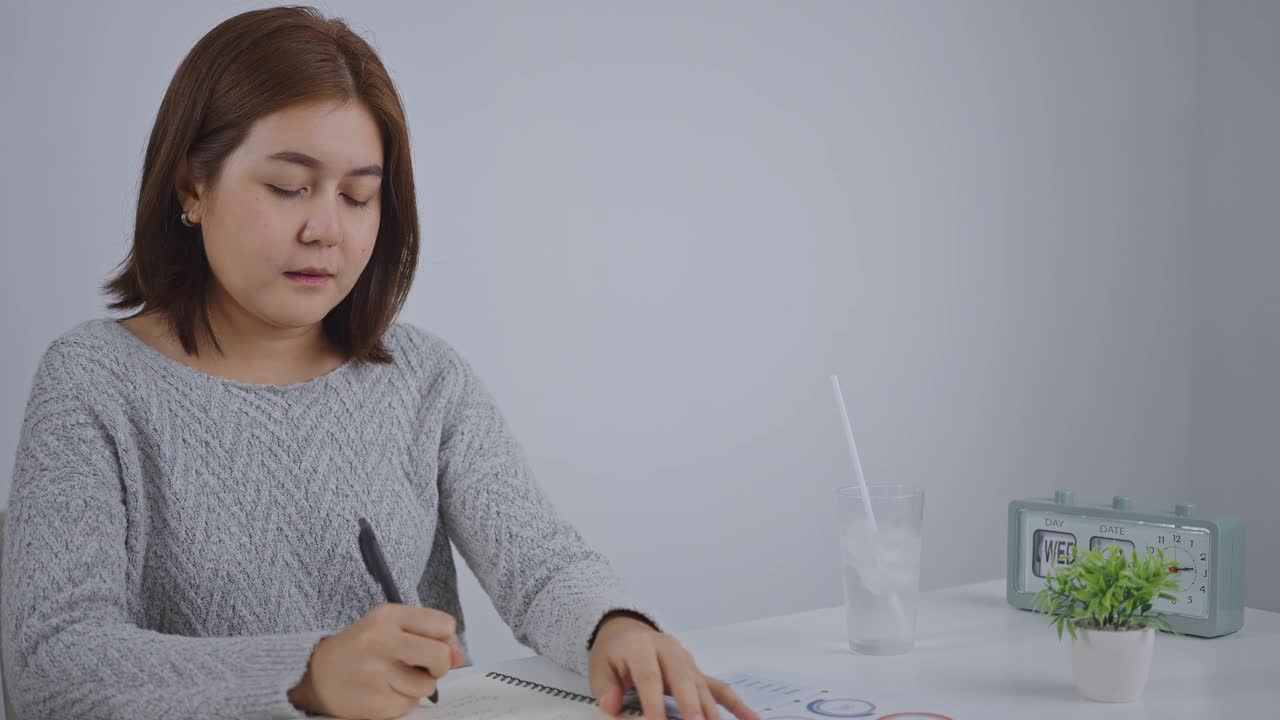 年轻的亚洲女子用吸管从玻璃杯里喝水。视频下载