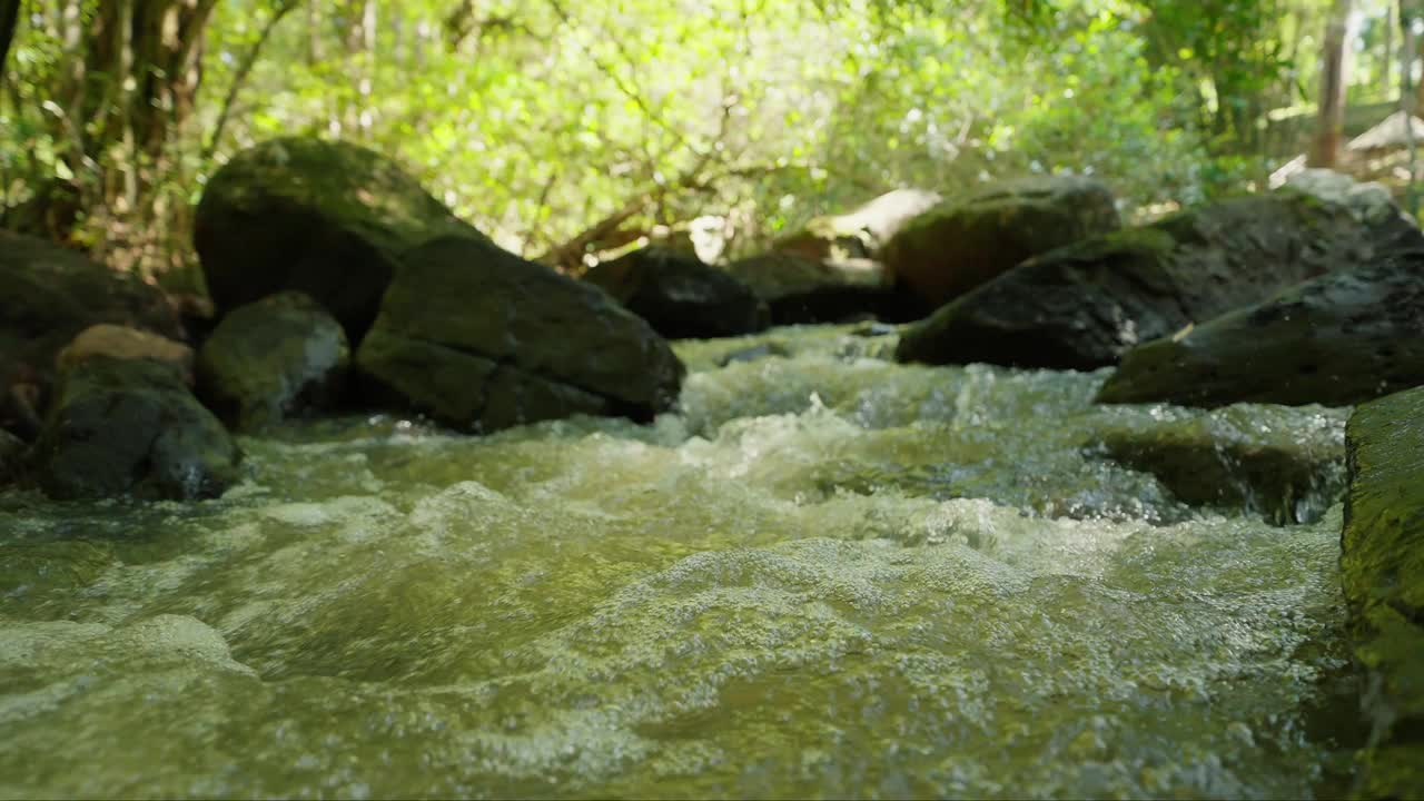 水从巨石中流过。石头在水里。水泡沫。快速的电流。丛林中水流穿过岩石的特写镜头。夏天流过岩石的小溪。自然概念视频素材