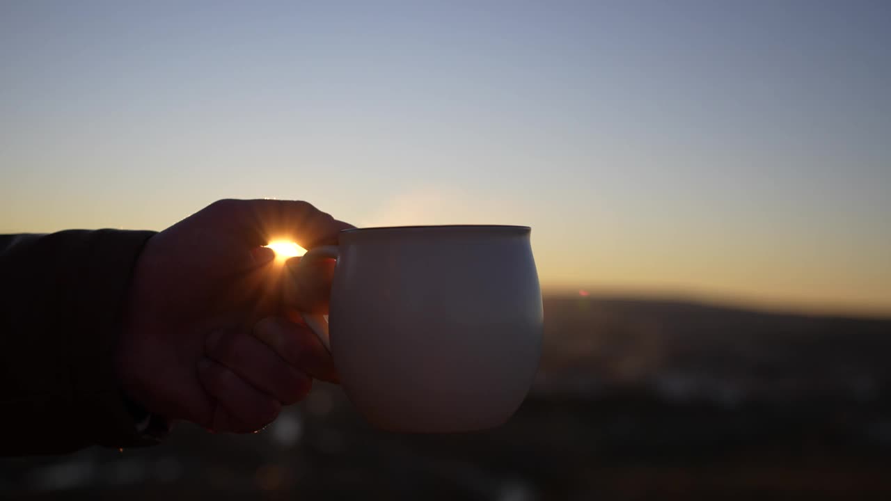 手持杯热饮夕阳背景。视频素材