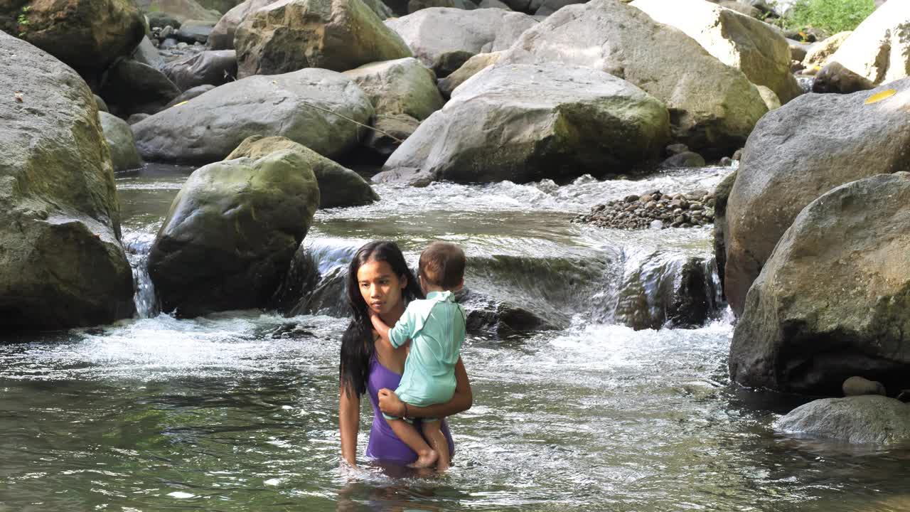 带着小婴儿的妇女从河中出来，撞上了大石头视频素材