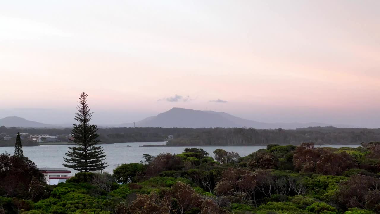 黄昏的宁静笼罩着海岸景观，山的剪影映衬着柔和的天空视频素材