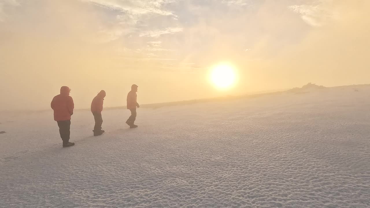 在日落和大雾的天气里，登山队正在高海拔的山顶上行走视频素材