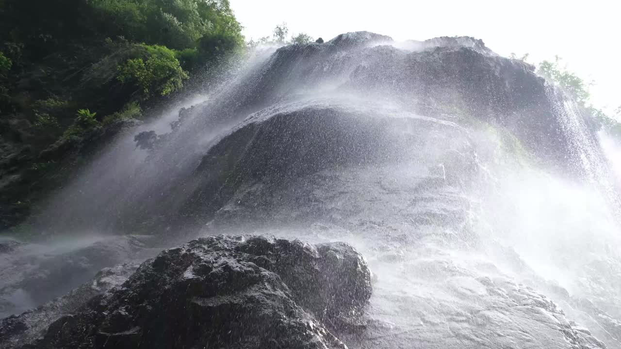 瀑布从山顶的岩石上倾泻而下，营造出如梦似幻的柔和细雨效果视频下载